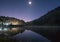 Pine forest light shine with the moon on reservoir at dawn