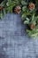 Pine and nobilis fir branches with cones on a background of dark gray tiles.