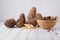 Pine nuts in a bamboo bowl next to cedar cones on a light background