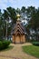 In a pine summer forest park there is a small wooden Christian church chapel . A path lined with stone tiles leads to it