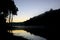 Pine tree in the forest with a lake in the foreground. Picture in sunrise time.