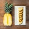 Pineapple fruit cut half and wedges and displayed on white plate and wooden background. Square Composition. Juicy organically gro