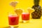 Pineapple juice in glass closeup near sliced fruit with spash and dripping liqid for summer vibes