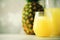 Pineapple juice in glassware and whole pineapple fruit on gray background. Copy space, sunlight effect. Summer, holiday