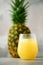 Pineapple juice in glassware and whole pineapple fruit on gray background. Copy space, sunlight effect. Summer, holiday