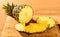 Pineapple juicy yellow fruit with slices and leaf on wooden background