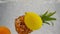 The pineapple, orange and lemon falls into the water with a lot of small bubbles. Fruits on isolated white background.