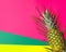 Pineapple on palm leaf on multicolored fuchsia pink green yellow background. Summer vacation tropical fruits beach party