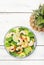 Pineapple shrimp salad with spinach, avocado and lime on white wooden kitchen table, top view. Healthy eating, balanced, clean