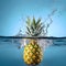 Pineapple splashes into the water on blue background