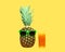 Pineapple with sunglasses and glass fruit juice on yellow background