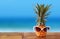 Pineapple with sunglasses on the table. Beach and tropical theme.