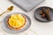 Pineapple tart or tartlet with grated coconut by a golden spoon and a small plate with cinnamon sticks on a white table cloth