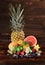 Pineapple, vivid grapefruit, pears, strawberries, leaves of mint, blueberries, lime and ice on a wooden brown background