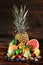 Pineapple, vivid grapefruit, pears, strawberries, leaves of mint, blueberries, lime and ice on a wooden brown background