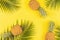 Pineapples and tropical palm leaves on yellow background. Top view, mockup, template, overhead. Summer concept. Creative flat lay