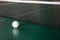 A ping-pong ball on a green table next to the net