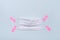Pink adhesive tape attaches protective mask on blue background. Global pandemic concept, copy space