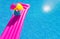 Pink air bed and beachball on swimming pool