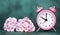 Pink alarm clock and flowers on blue background, spring, daylight savings time concept