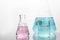 Pink andpink and blue solution in beaker and flask in white science laboratory background