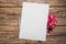 Pink azalea flowers with silver color pencil and empty paper sheet on a wooden background, top view, space for text, flat lay