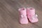 Pink baby booties on wooden surface