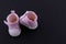 Pink baby shoes on a black background. The concept of first steps, birthday, expectation, pregnancy, motherhood, motherhood,