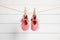 Pink baby shoes drying on washing line against white wall