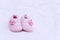 pink baby shoes on white bed in the bedroom. Close up cotton pink footwear for newborn in the room