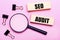 On a pink background, a magnifier, black paper clips and wooden blocks with the text SEO AUDIT. Business concept