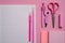 On a pink background, school accessories and a pen, colored pencils, a pair of compasses, a pair of compasses, Copy space, top vie