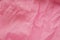 Pink background from a textile material with wicker pattern, closeup. Cloth backdrop. Crumpled fabric. Selective focus