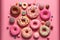 Pink background with various donuts and sprinkles