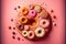 Pink background with various donuts and sprinkles