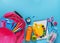 Pink backpack, fruit smoothie bottle,and stationery on blue background. Top view, copy space