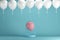 Pink balloon floating in white cage on blue background with white balloons.