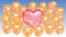 Pink balloon in the shape of a heart surrounded by golden balloons on a blue sky background. Seamless looping