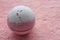 Pink bath bomb on soft towel texture background. Handmade salt ball like cake. Bath spa accessories.