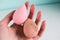 Pink beauty tear-shaped blender, dirty and clean sponges  on white background. Cosmetic tool for makeup in hand.