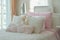 Pink and beige pillows on bed next to window