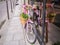 Pink bicycle decorated with flowers leans against a shop window