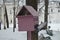 Pink birdhouse on a tree and soaring dove next to it