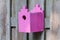 Pink birdhouse on a wooden fence