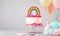 Pink Birthday Cake with Rainbow decoration and balloons at a Party