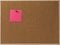 Pink Blank sticky notes red pinned into brown corkboard.