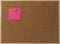 Pink Blank sticky notes yellow pinned into brown corkboard.