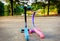 Pink and blue color children scooter parked on road in front of lake