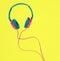 Pink and blue headphones on a yellow background. Minimal music concept with copy space