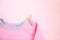 Pink bodysuit for children on a clothespin on a pink background